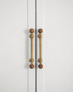 Walnut ball pulls on white wardrobe doors — vertical orientation