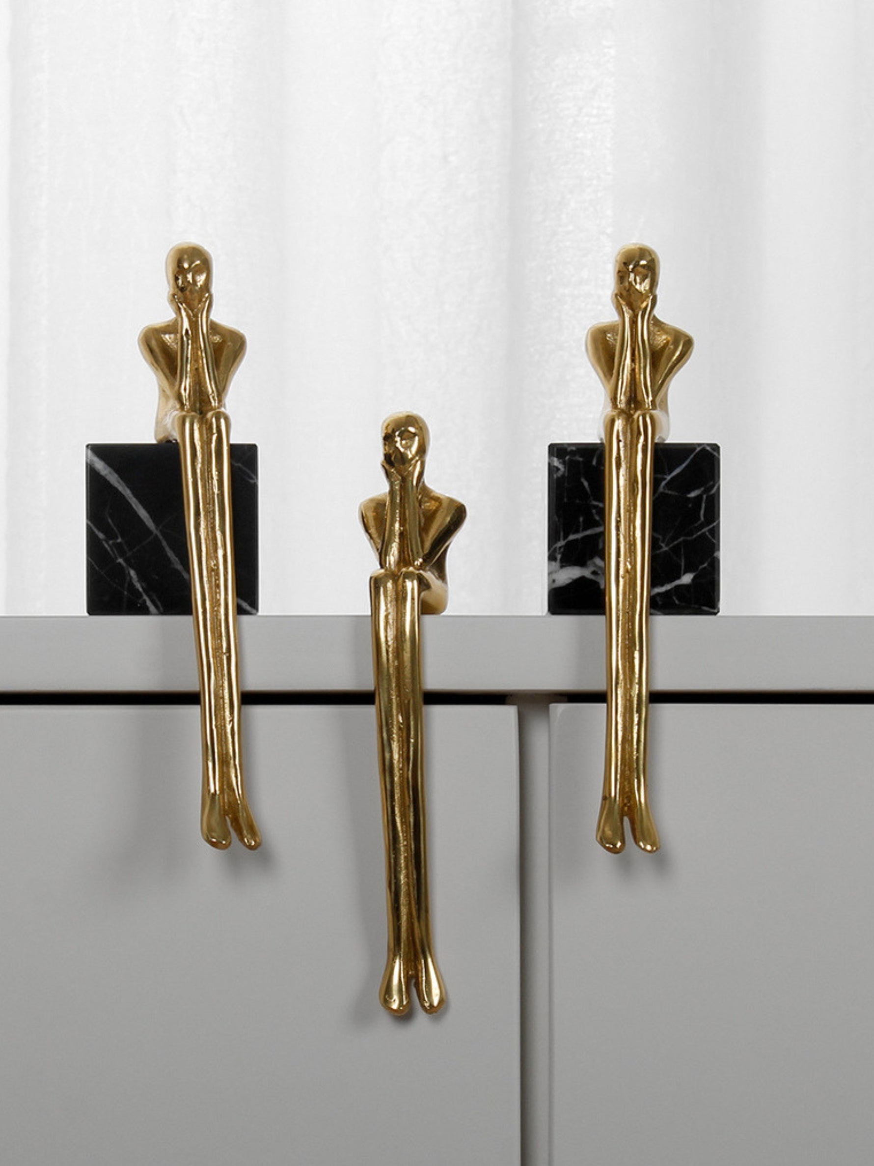 Three gold thinker figure pulls displayed on black marble base