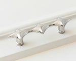 Polished chrome star cabinet pull on white surface, horizontal close-up