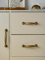 Antique brass beaded bar pulls on greige chest of drawers — styled