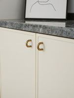 White cabinet with brushed brass handles and a gray marble countertop.