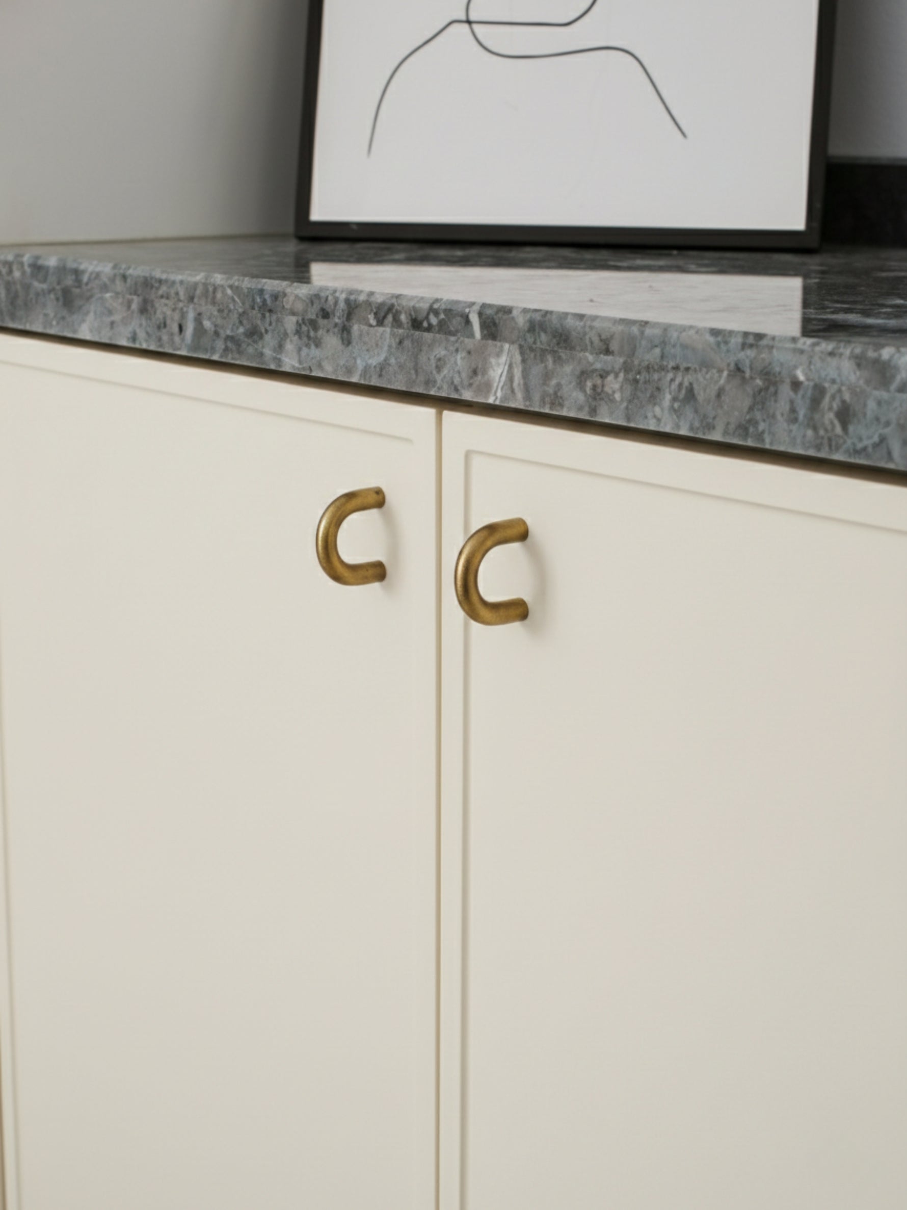White cabinet with brushed brass handles and a gray marble countertop.