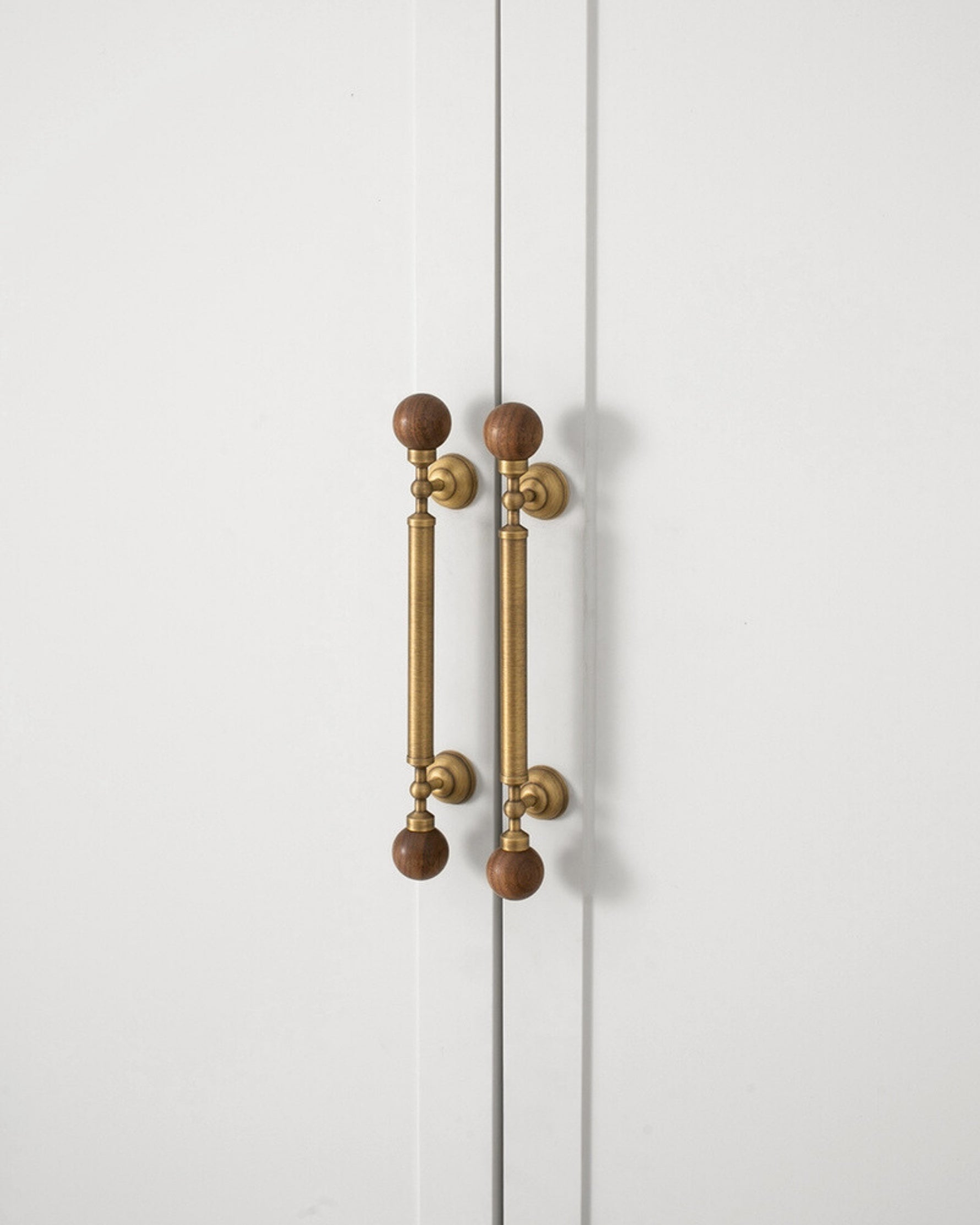 Walnut ball pulls on white cabinet doors — front view