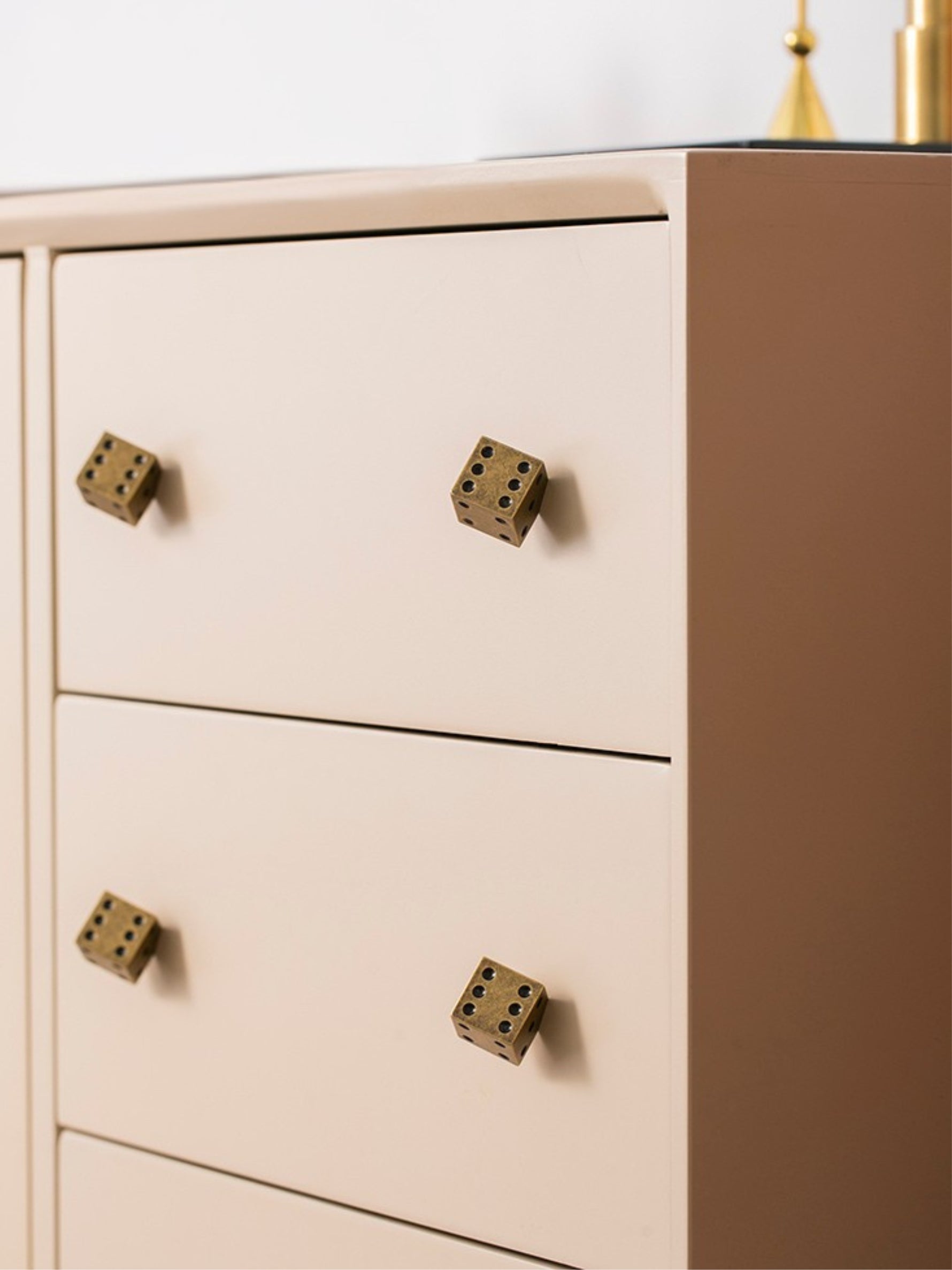 Antique brass dice knobs on blush pink chest of drawers