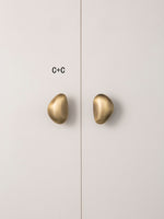 Size C brushed brass pebble knobs paired on wardrobe