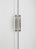 Two antique silver reeded pulls on white cabinet doors, front view