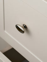 Nickel silver oval knob on drawer front, angled close-up view