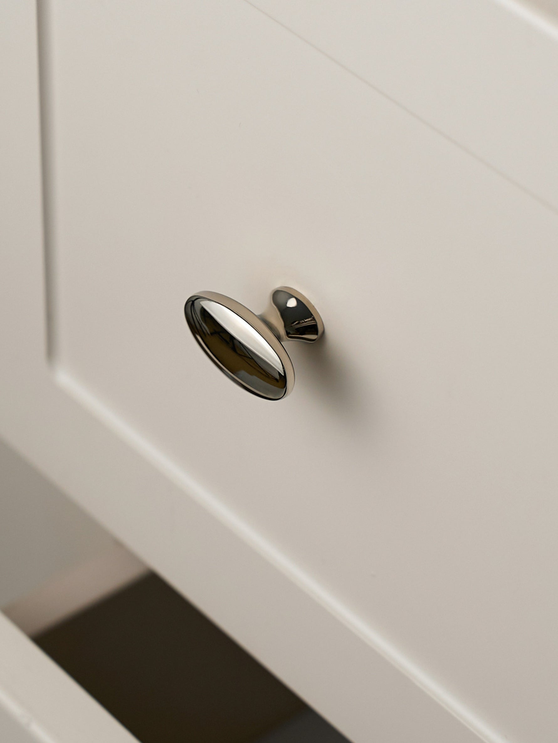 Nickel silver oval knob on drawer front, angled close-up view