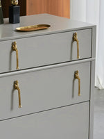 Gold thinker figure pulls on grey chest of drawers — bedroom styling