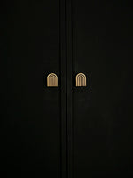 Pair of solid brass Art Deco arch knobs mounted on dark wardrobe doors