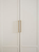 Close-up of a light gray cabinet with antique brass handles