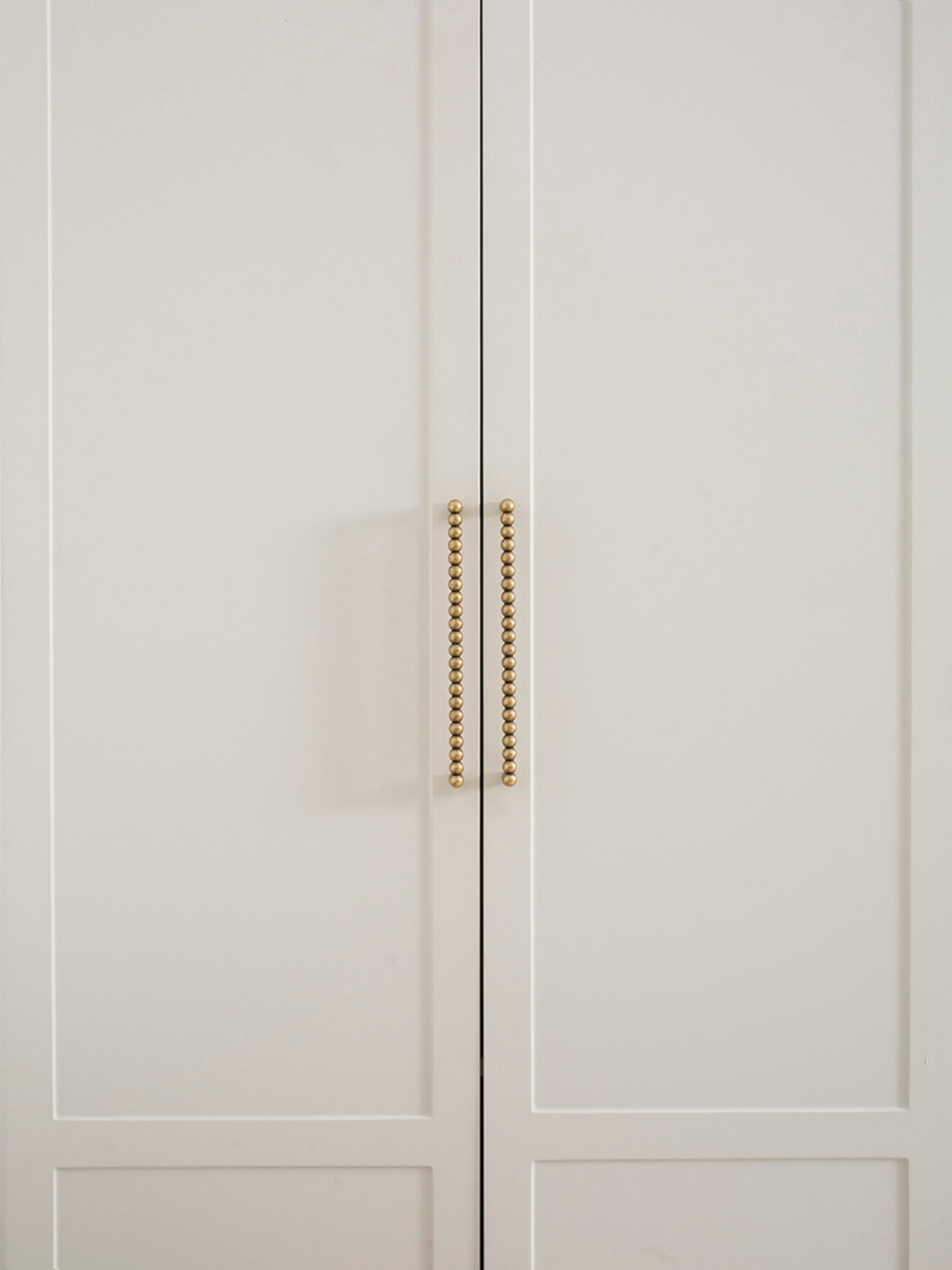 Close-up of a light gray cabinet with antique brass handles