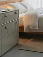 Gold thinker figure pulls on grey bedside drawer cabinet