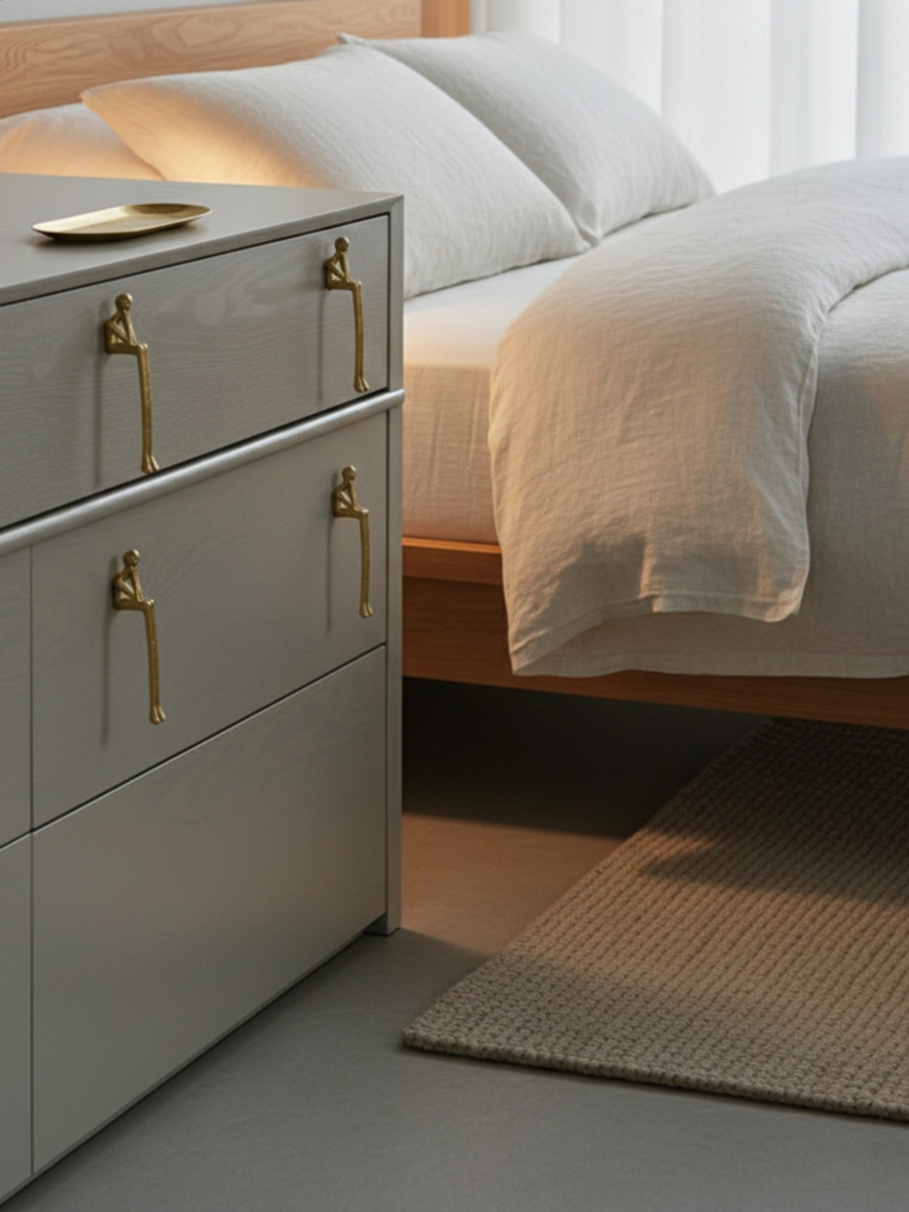 Gold thinker figure pulls on grey bedside drawer cabinet