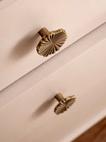 Antique brass ginkgo knob on white drawer — side angle