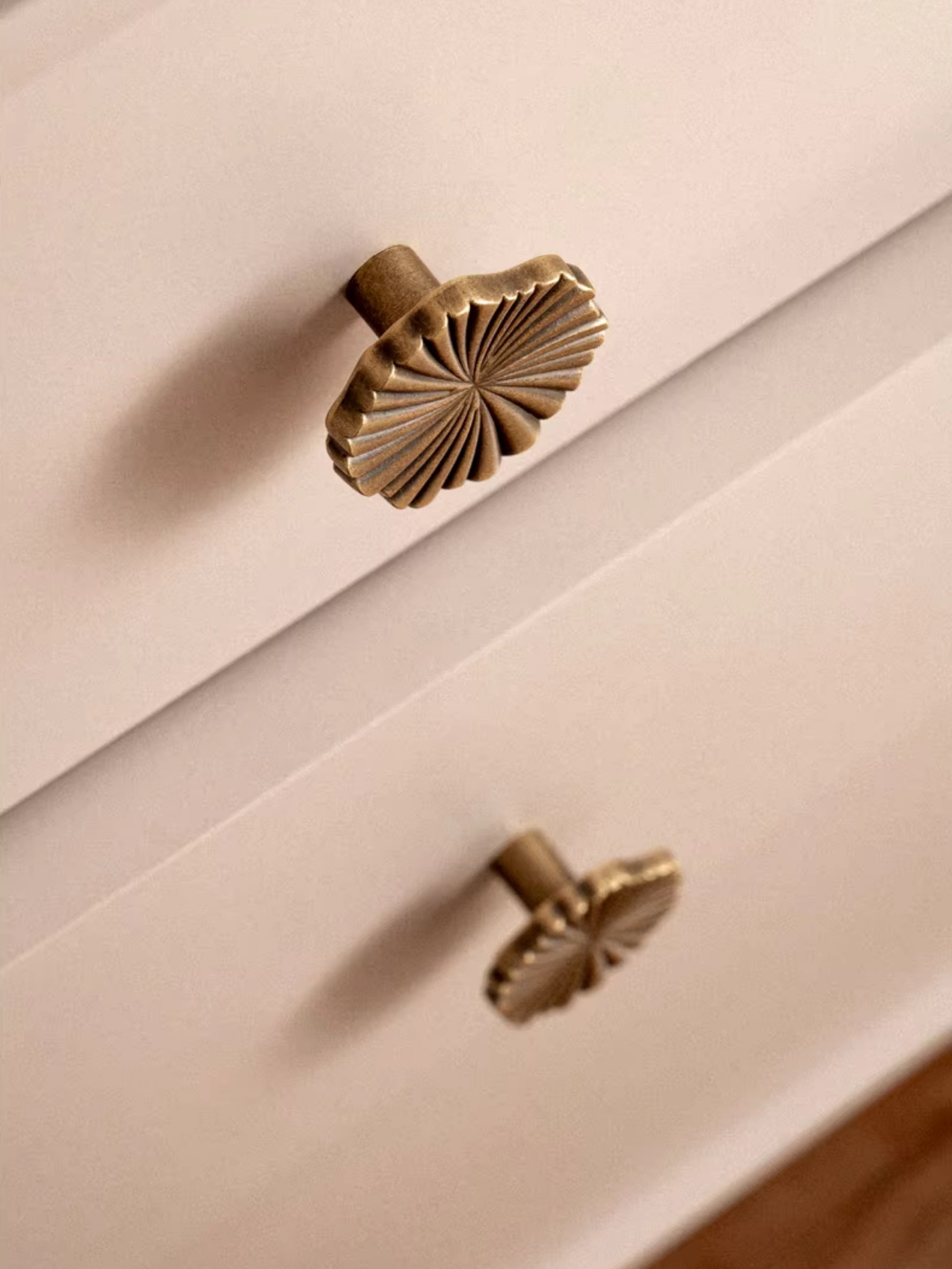 Antique brass ginkgo knob on white drawer — side angle