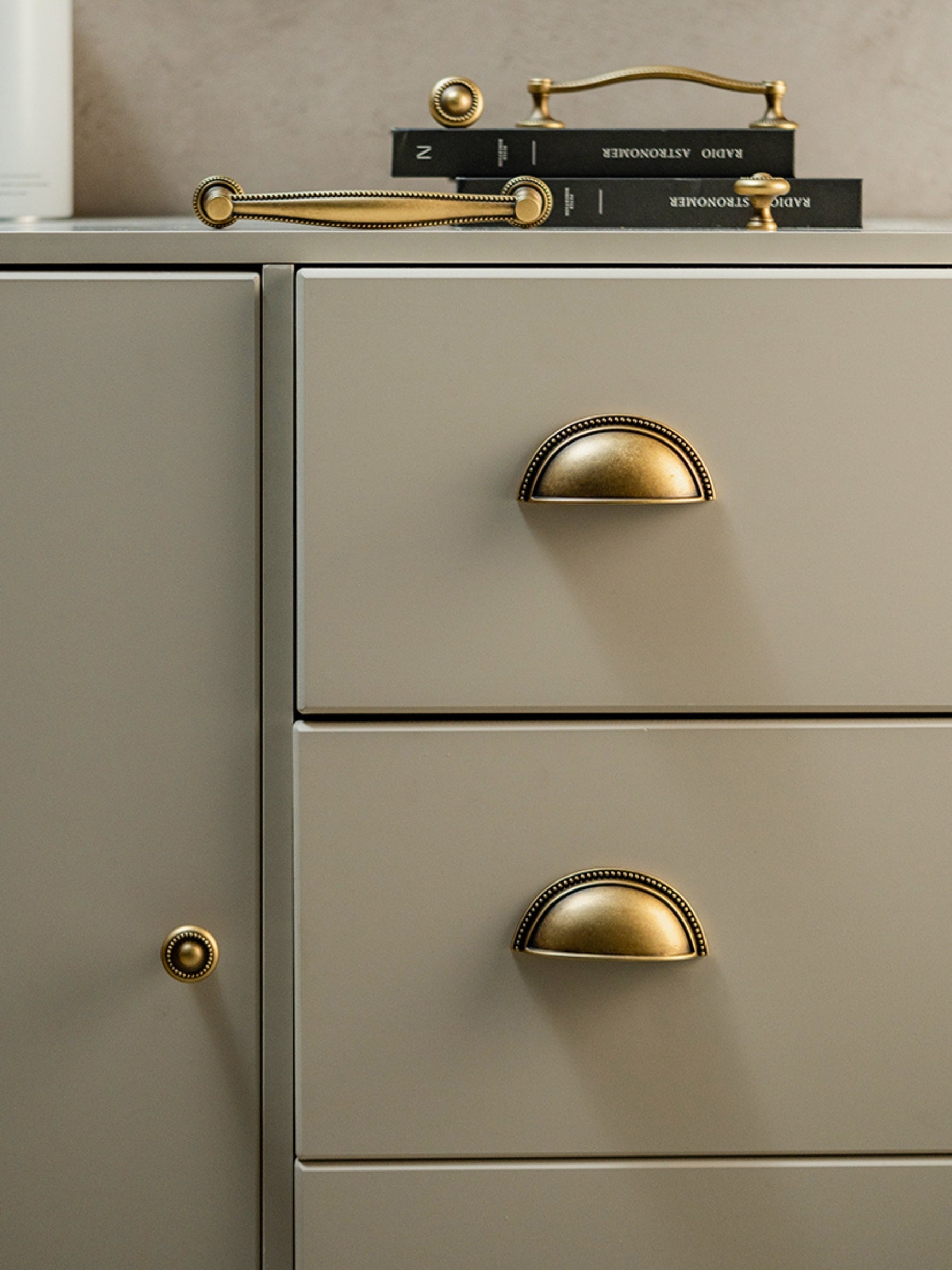 Antique brass beaded cup pulls on grey drawers with knob on cabinet door