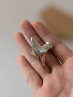 Polished chrome star cabinet knob held in open palm, close-up