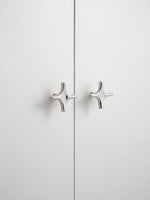 Close-up polished chrome star knobs on white cabinet doors