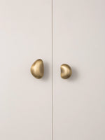 Brushed brass pebble cabinet knobs on white wardrobe door