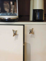 Chrome-tone wave star knobs installed on cream vintage cabinet with retro kitchen appliances