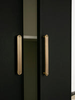 Tall solid brass Art Deco arch door pull on black wardrobe — vertical orientation