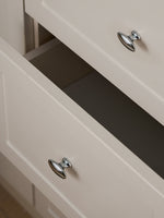 Polished chrome oval knobs on open cream drawer fronts