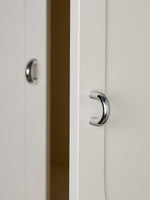 Two polished chrome cup pulls on white cabinet doors, close-up