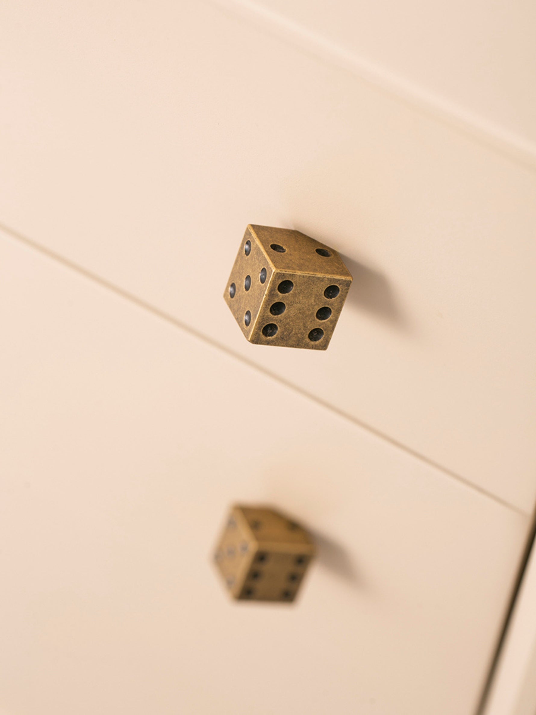 Close-up antique brass dice knob on white cabinet — detail shot