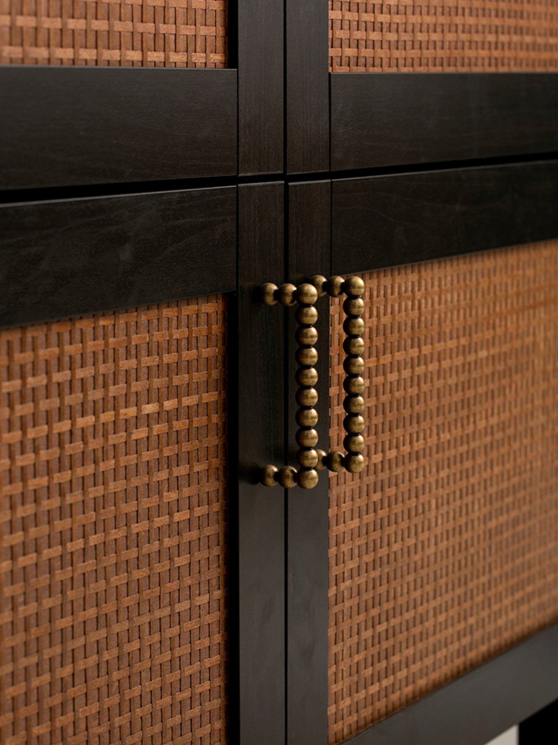 Close-up of a cabinet with woven texture and antique brass handle
