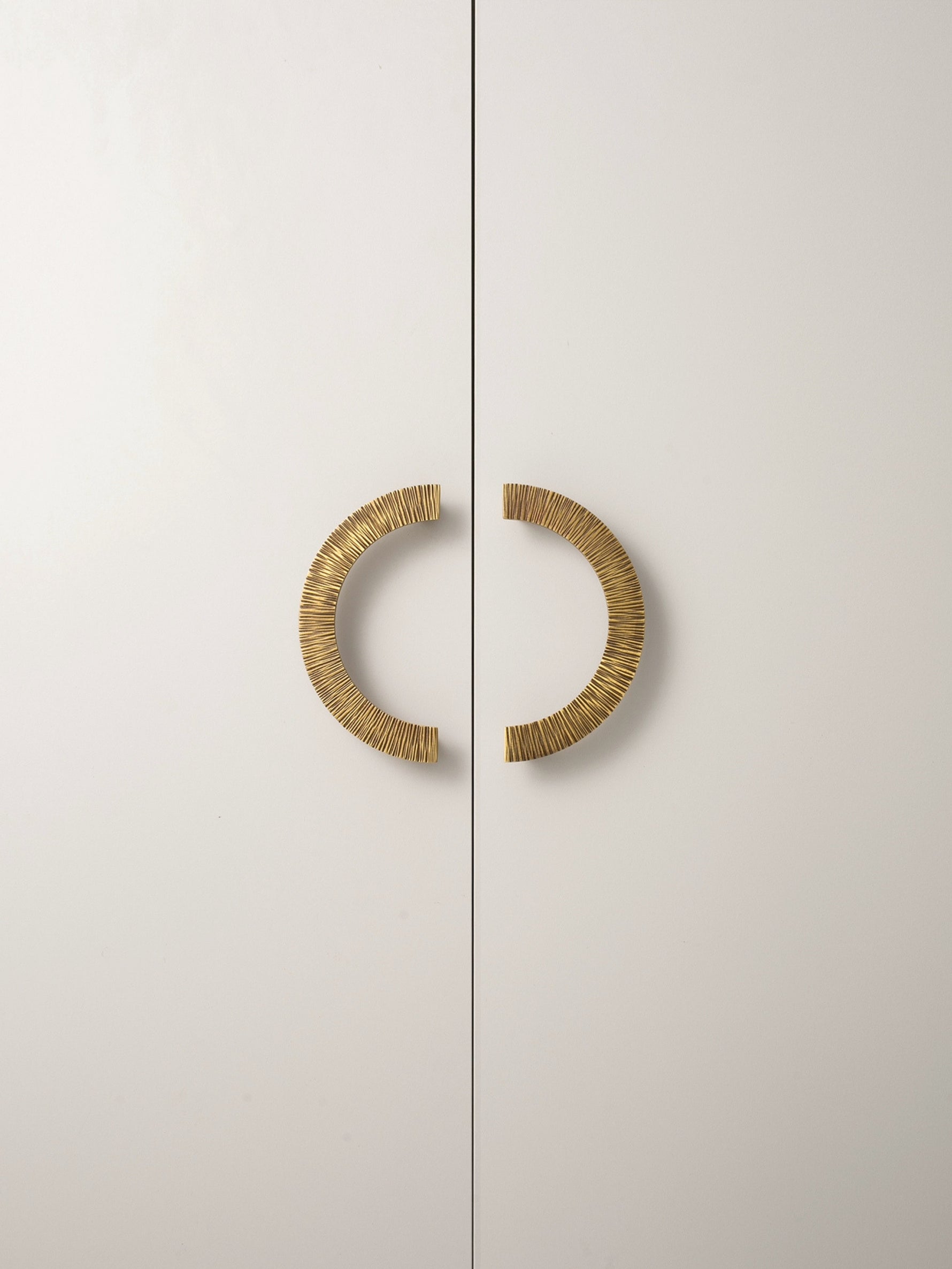 Antique brass sunray arch pulls on white wardrobe doors