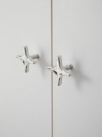 Two polished chrome star knobs on white cabinet doors with visible mounting posts