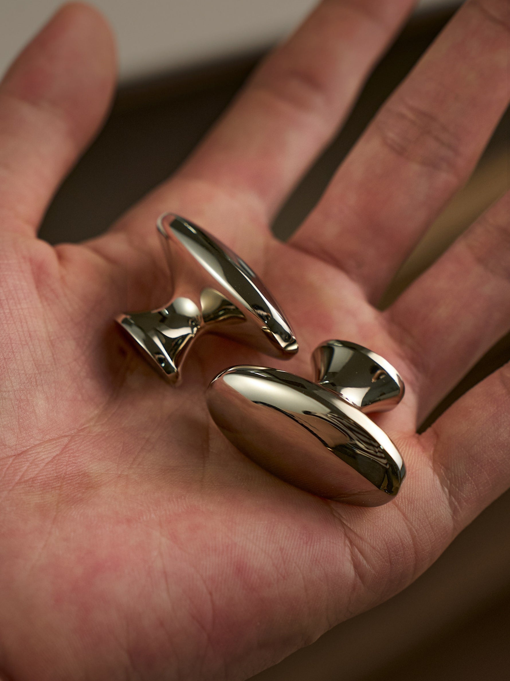 Two nickel silver oval cabinet knobs in hand, macro close-up