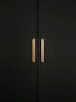 Close-up pair of solid brass Art Deco arch pulls on matte black wardrobe doors