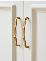 Antique brass wavy bamboo pulls on white wardrobe doors