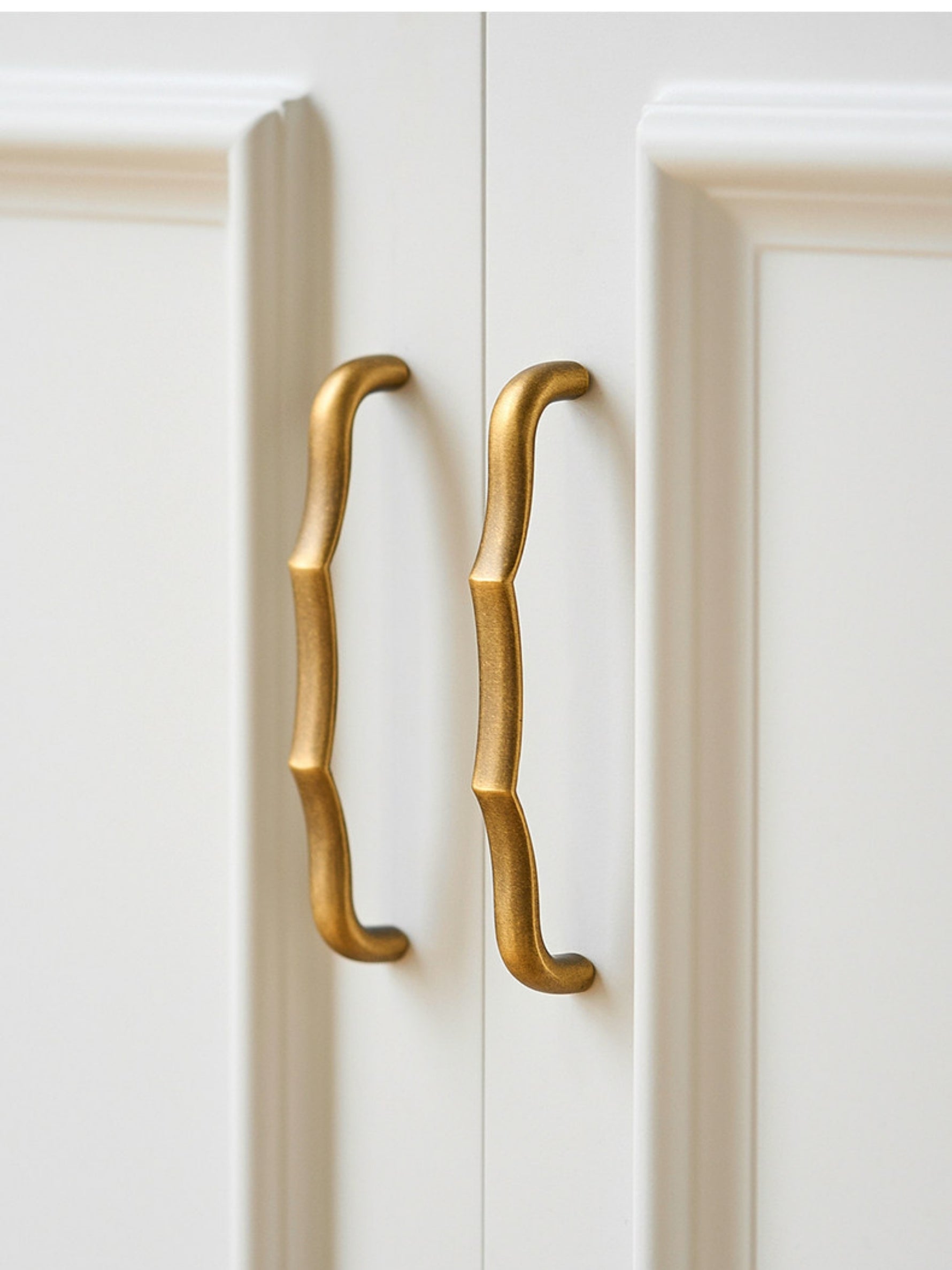 Antique brass wavy bamboo pulls on white wardrobe doors