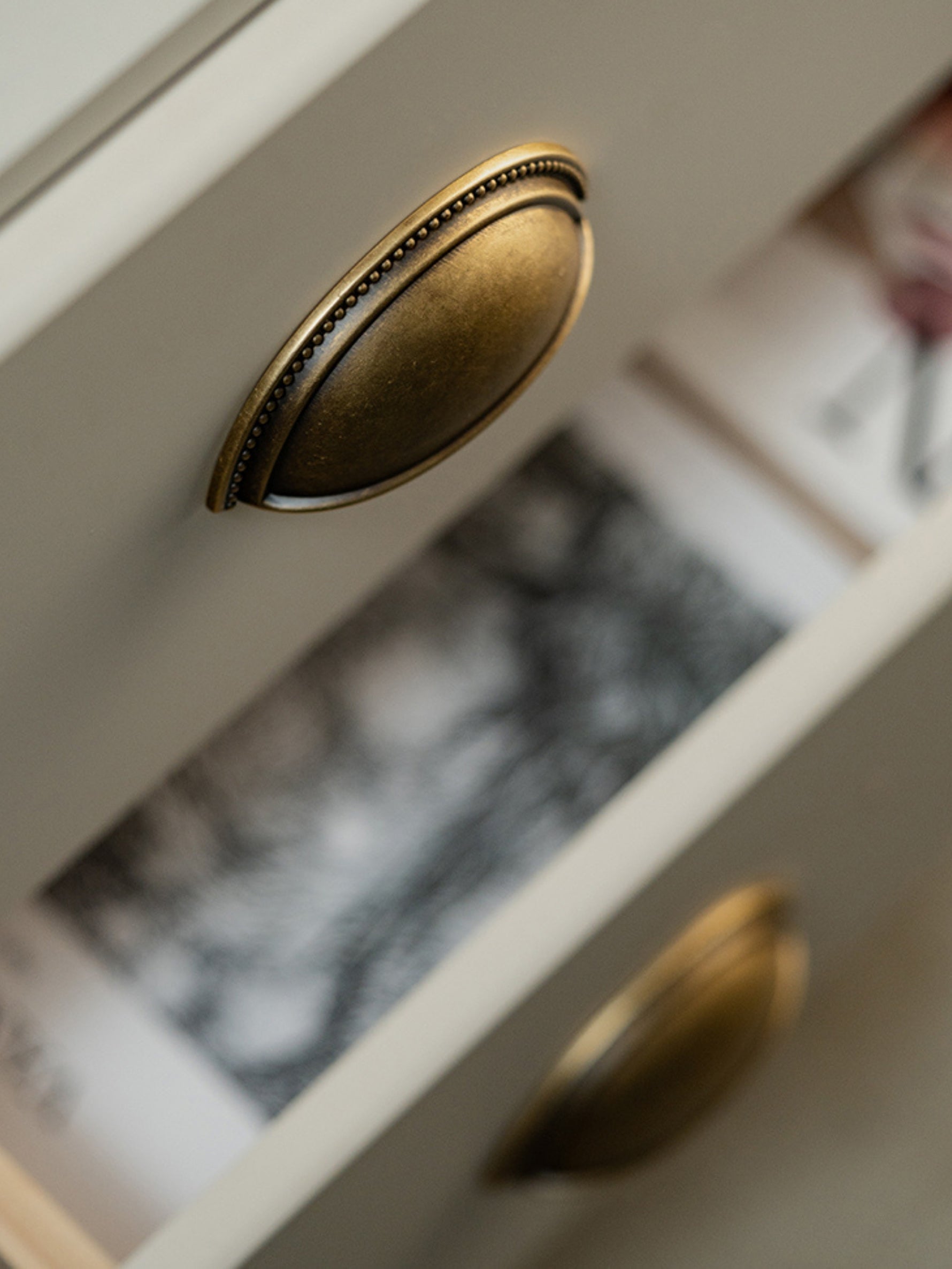 Antique brass beaded cup pull on open drawer — close-up detail