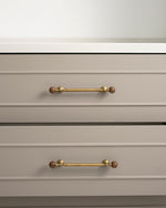 Antique brass walnut ball pulls on greige kitchen drawer fronts