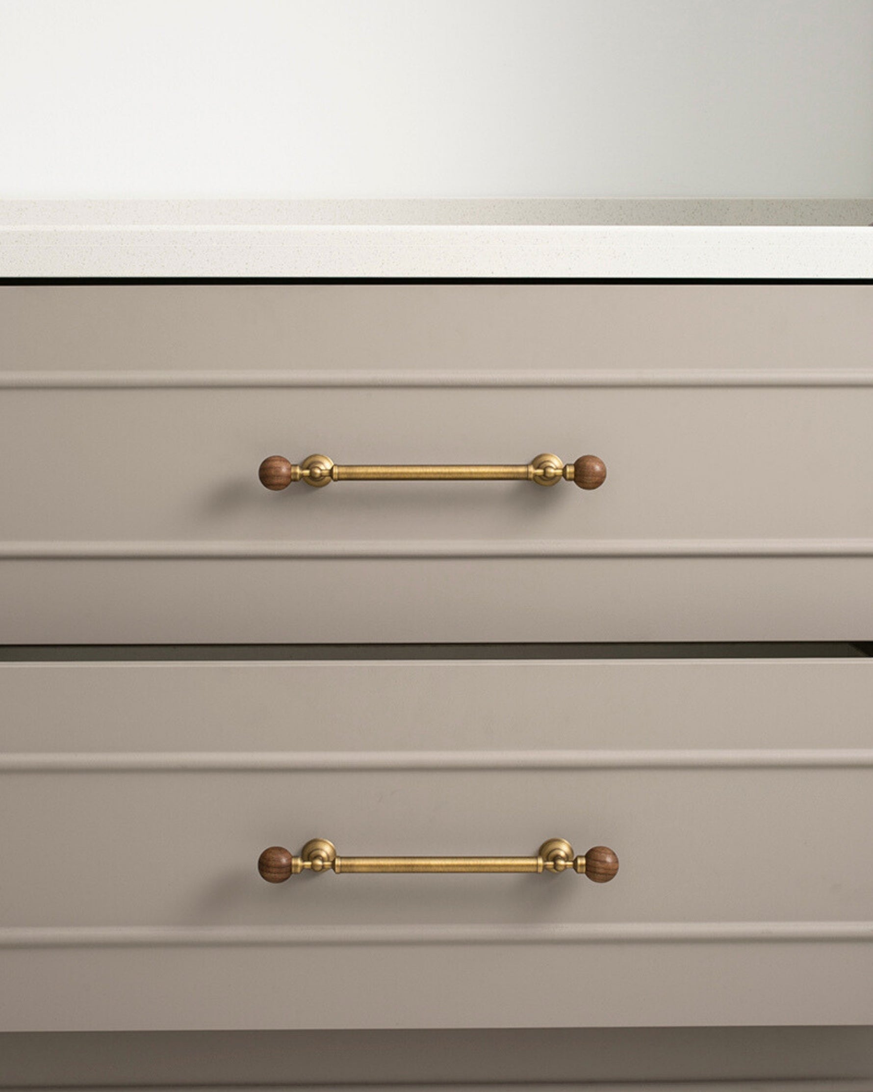 Antique brass walnut ball pulls on greige kitchen drawer fronts