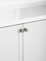 Two antique silver knobs on white shaker kitchen cabinet under stone countertop