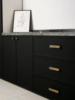 Black kitchen cabinetry with solid brass Art Deco arch drawer pulls and knob, marble countertop styling