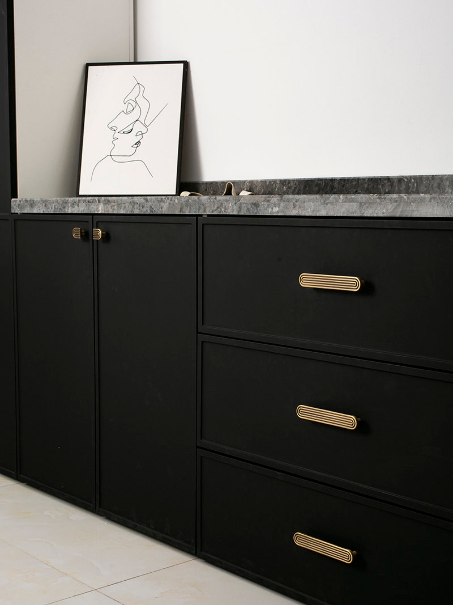 Black kitchen cabinetry with solid brass Art Deco arch drawer pulls and knob, marble countertop styling