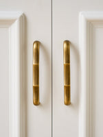 Antique brass straight bamboo pulls on white cabinet doors