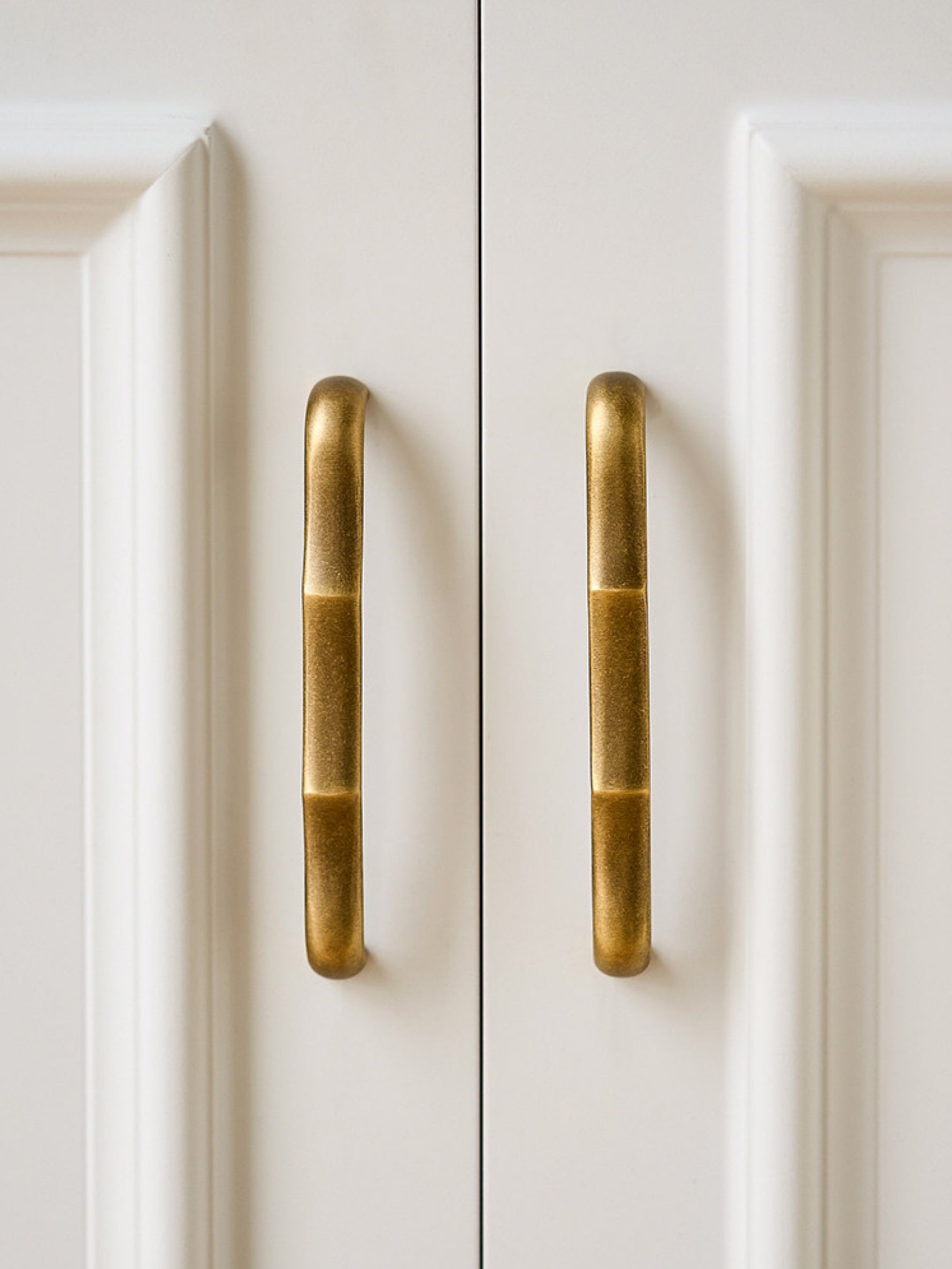 Antique brass straight bamboo pulls on white cabinet doors