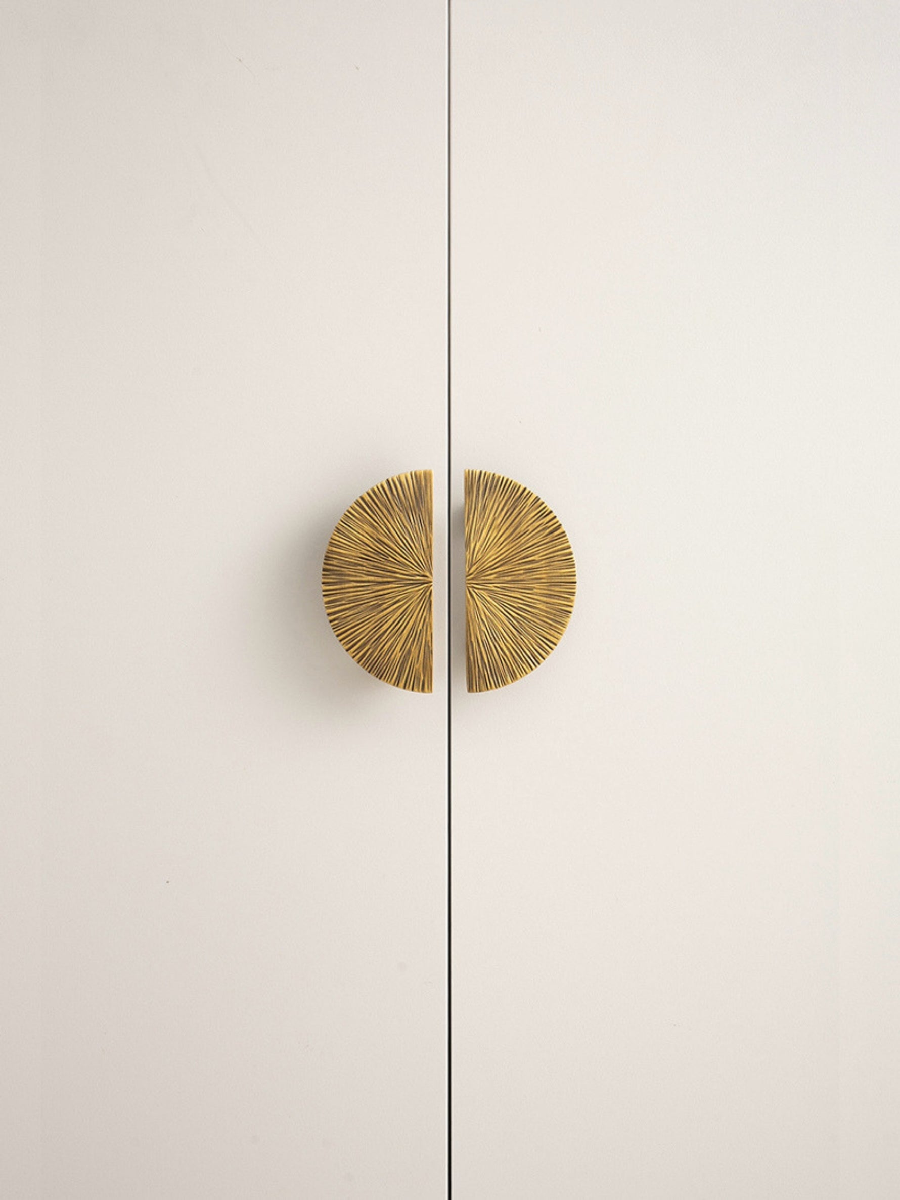 Antique brass sunray half-moon pulls on white cabinet doors