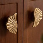 Antique brass ginkgo split pull on walnut cabinet — close up