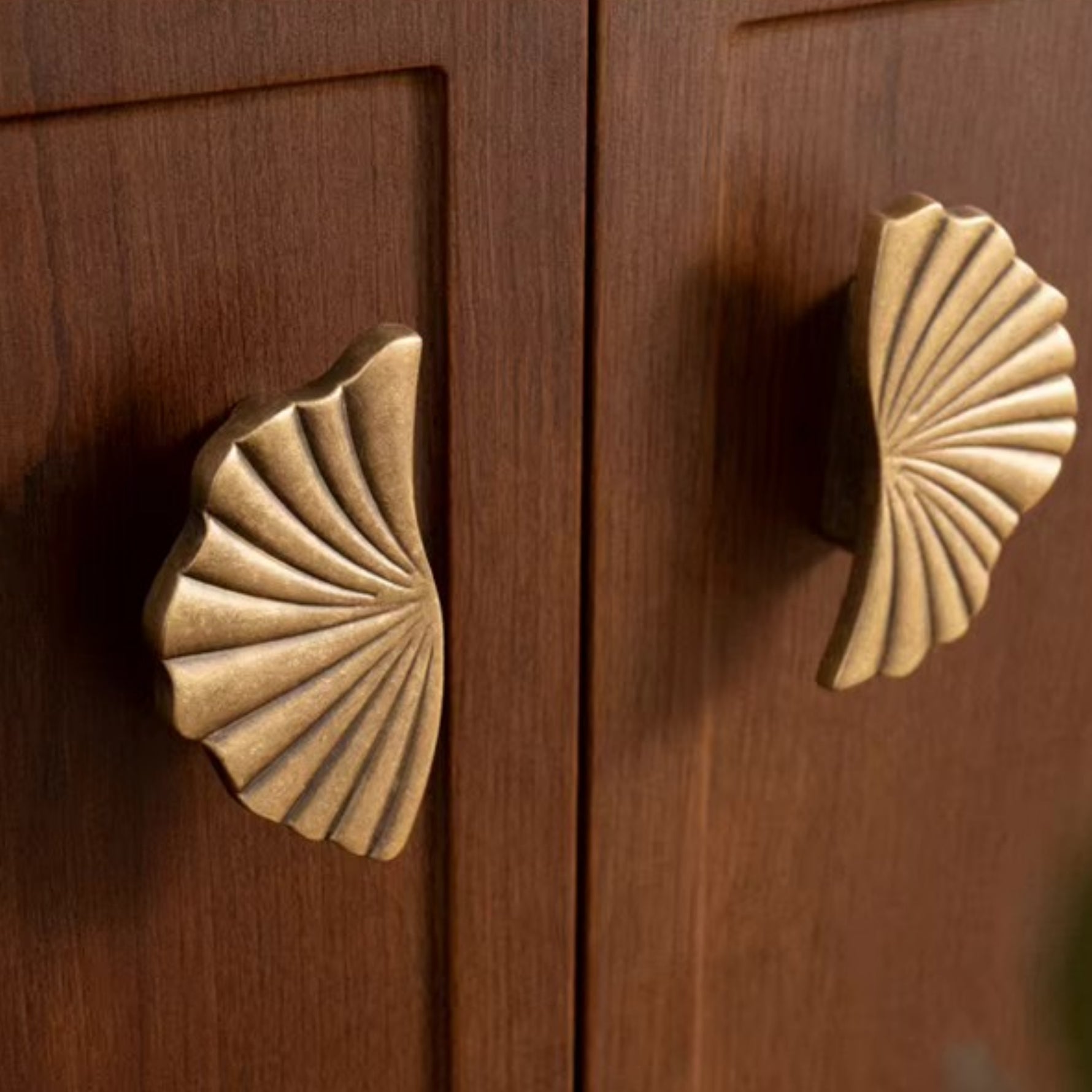 Antique brass ginkgo split pull on walnut cabinet — close up