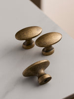 Three antique brass oval knobs on white marble surface