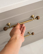 Hand pulling greige kitchen drawer with walnut ball brass handle
