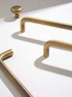 Close-up of brushed brass cabinet handles on a white surface